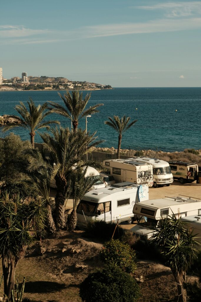 pexels-photo-30971401-30971401 Campers parked by the sea with palm trees, offering a scenic coastal view.